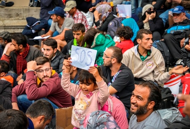 Groups of migrants and child with SOS sign