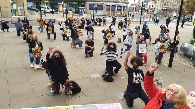 UK people kneeling with placards and flags