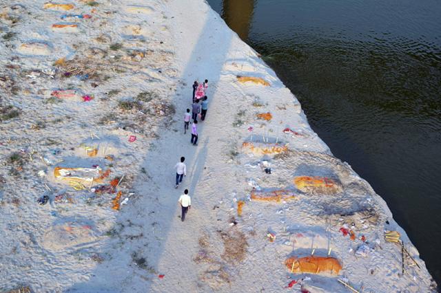 People caryring abody between other bodies buried in sand