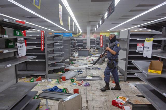 A police officer walks in a looted shop in Johannesburg, South Africa, on July 12, 2021.